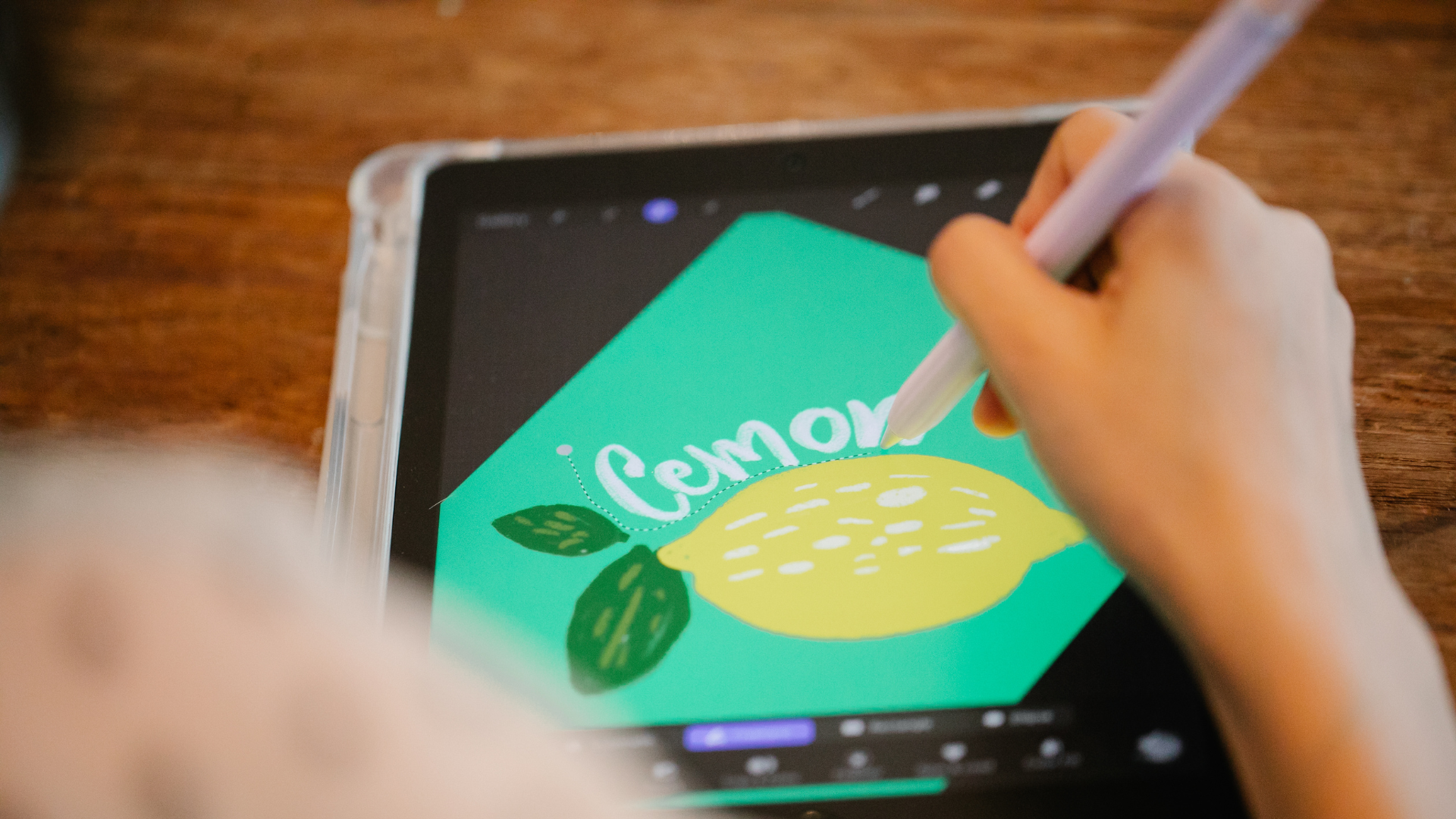 A digital artist draws a lemon using a tablet and digital pencil.